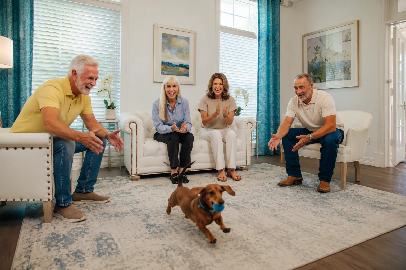 Group of adults chatting in a living room while a small brown dog runs across the rug