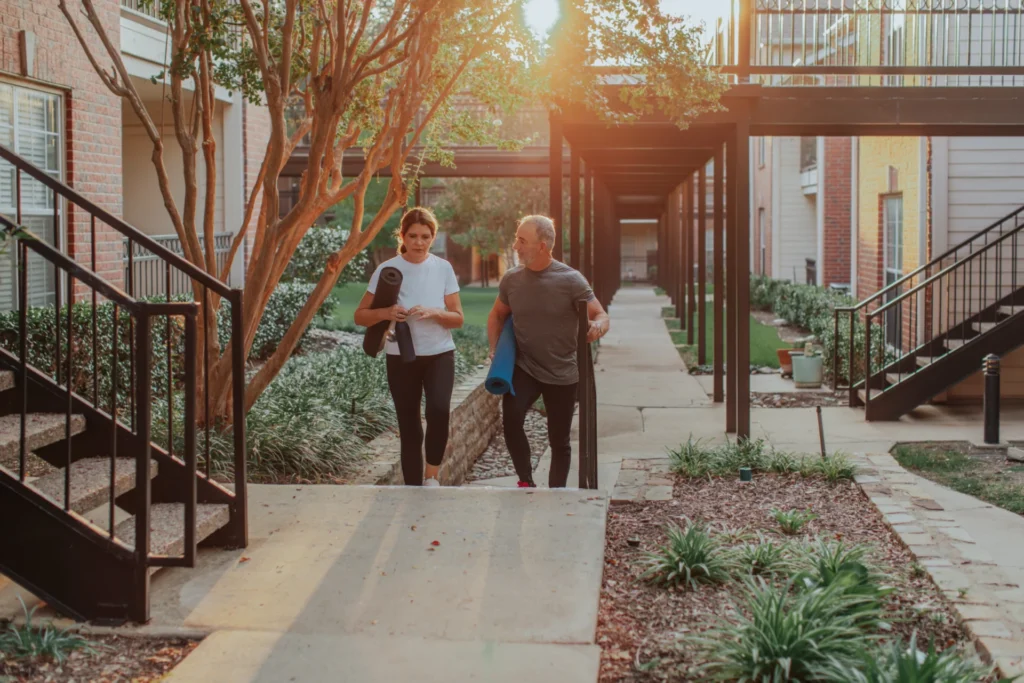 Two seniors walking with yogamats in the morning