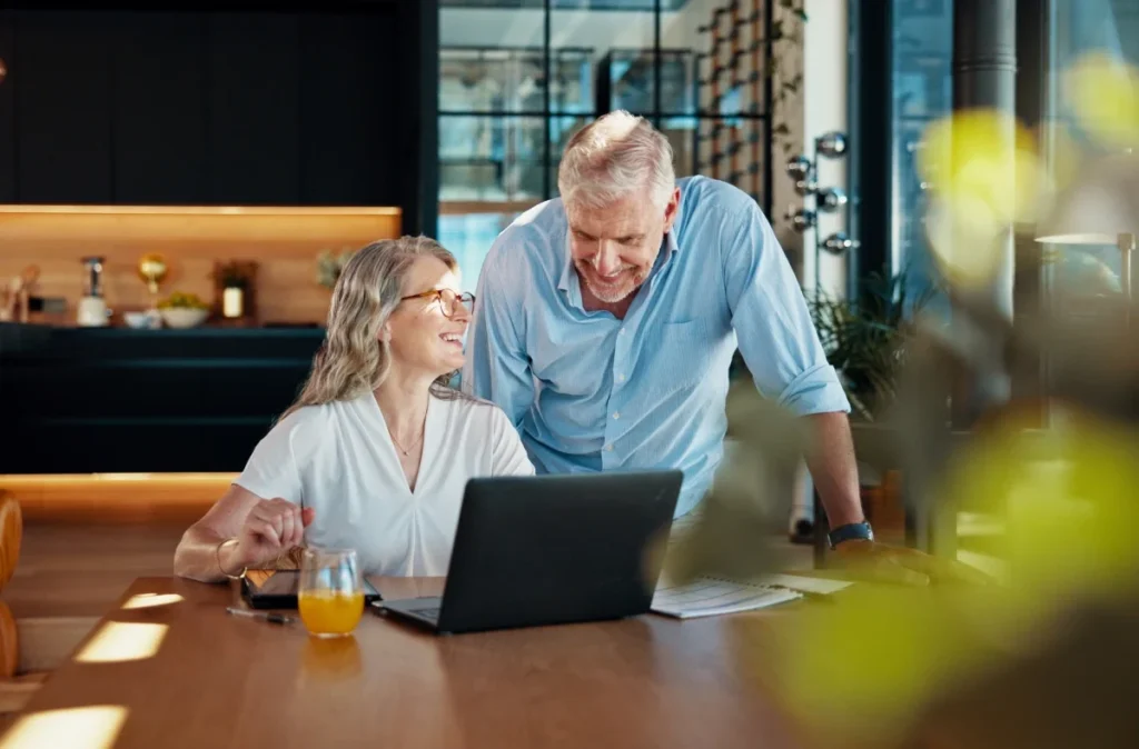 Older man and woman looking at a laptop together at a table